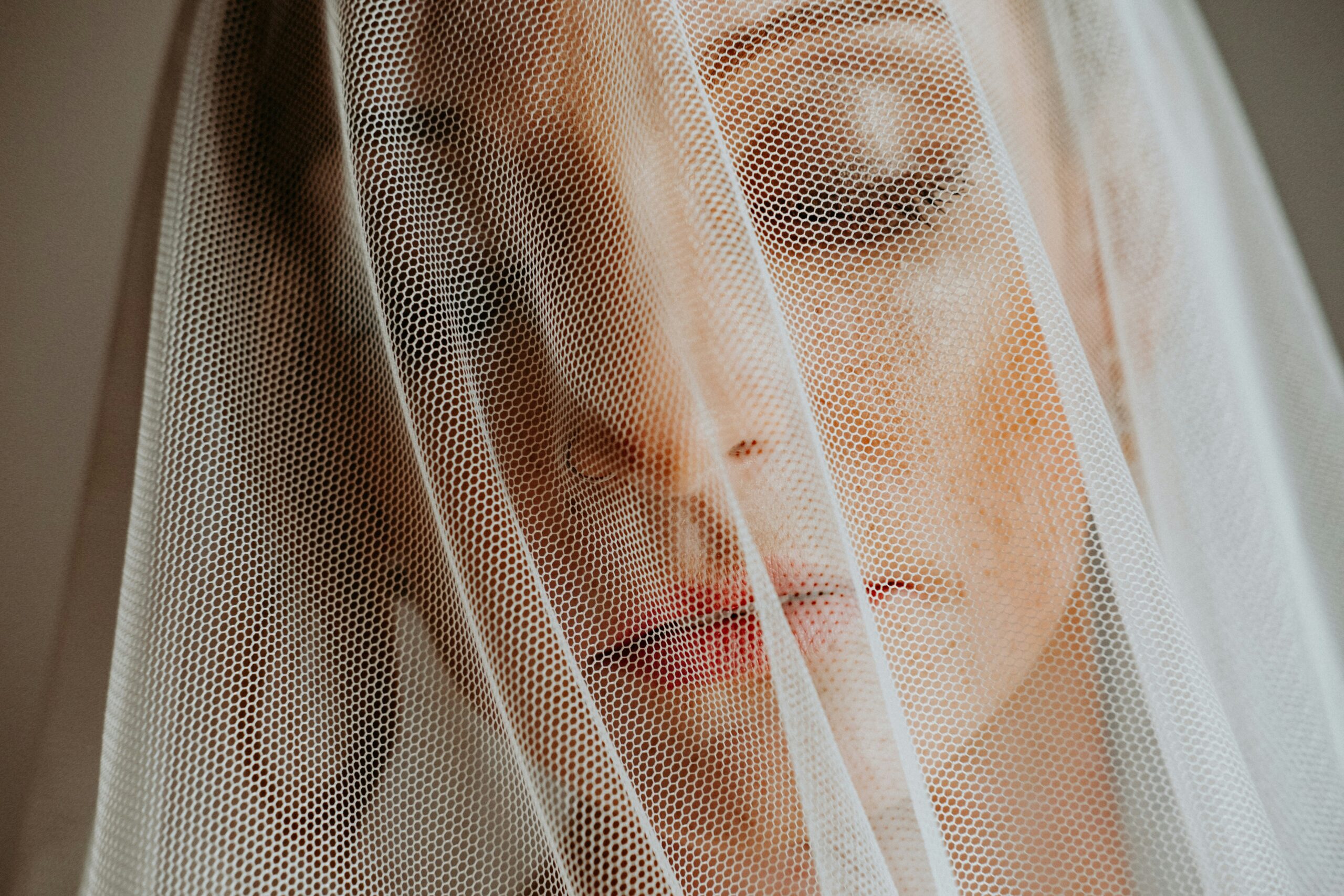 Smiling bride wearing a vintage-style rhinestone crown with her veil trailing behind.