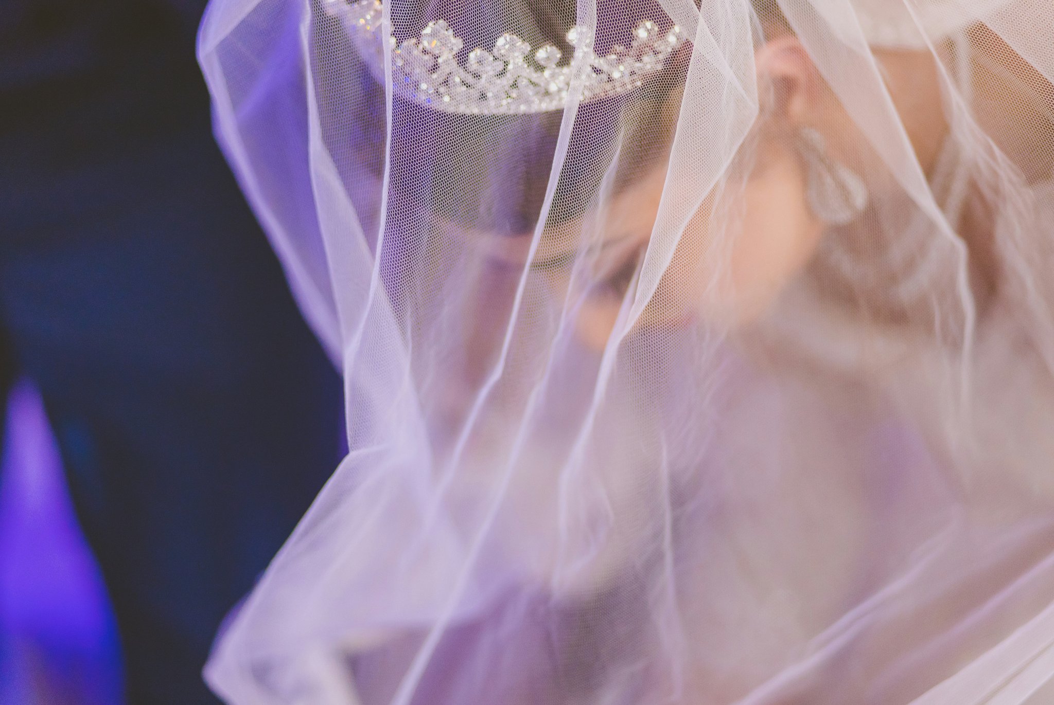 A bride practicing her hairstyle with a crystal bridal headpiece under natural daylight.