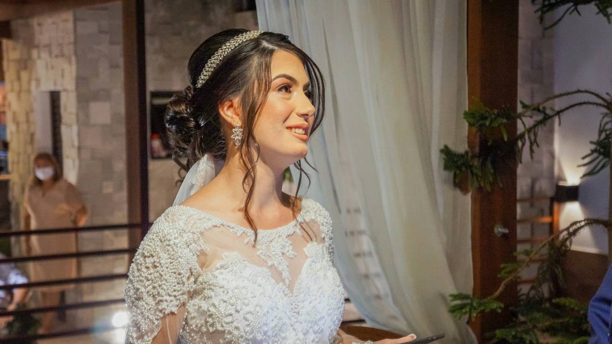 Happy bride wearing lace bridal hairpiece styled in half-up hairstyle