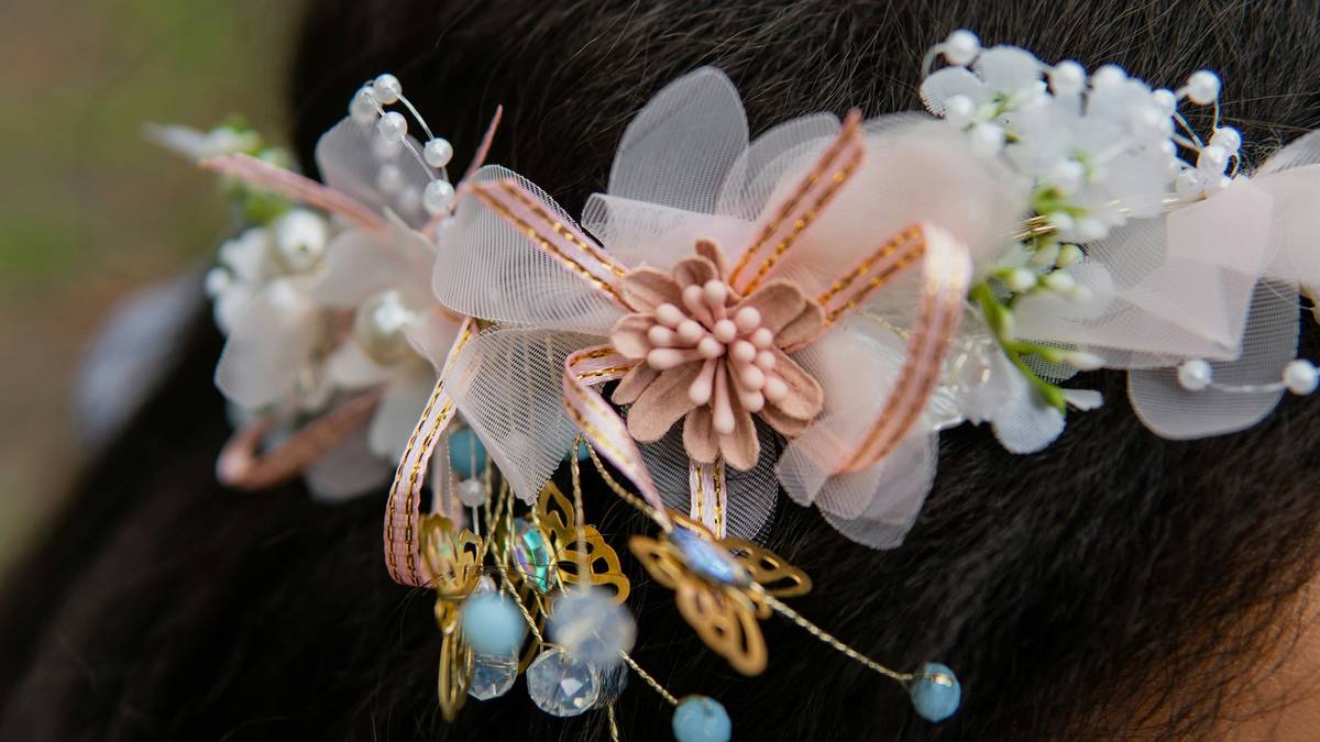 A bride trying on different modern bridal headpieces at a boutique store.