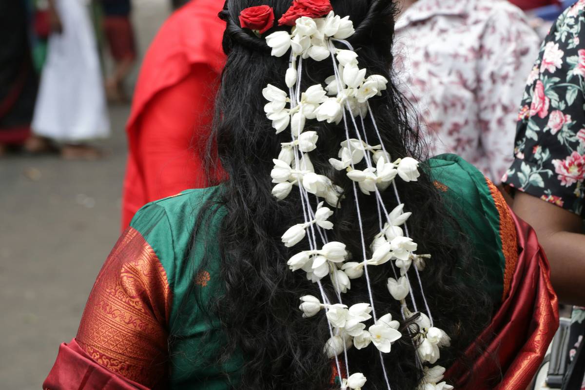 Close-up shot showing a woman adjusting a copper flower crown over wavy brown hair.