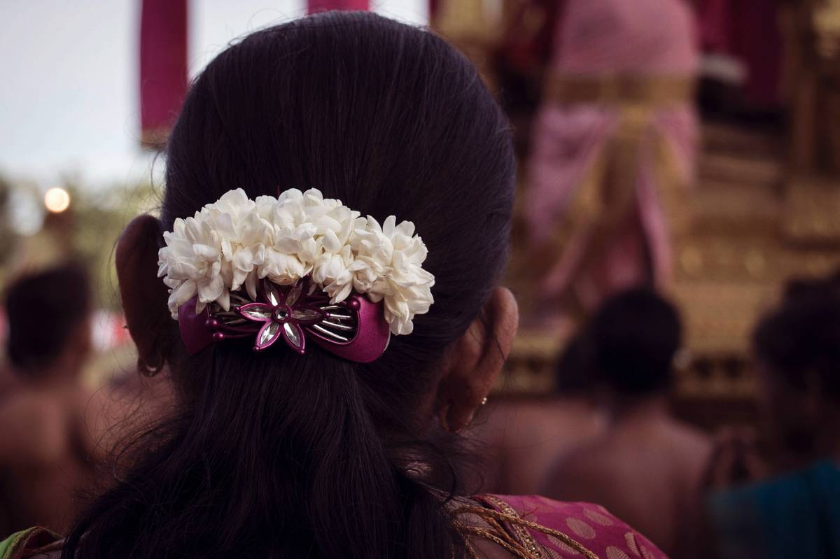 A model wearing a floral wedding crown with daisies and greenery.
