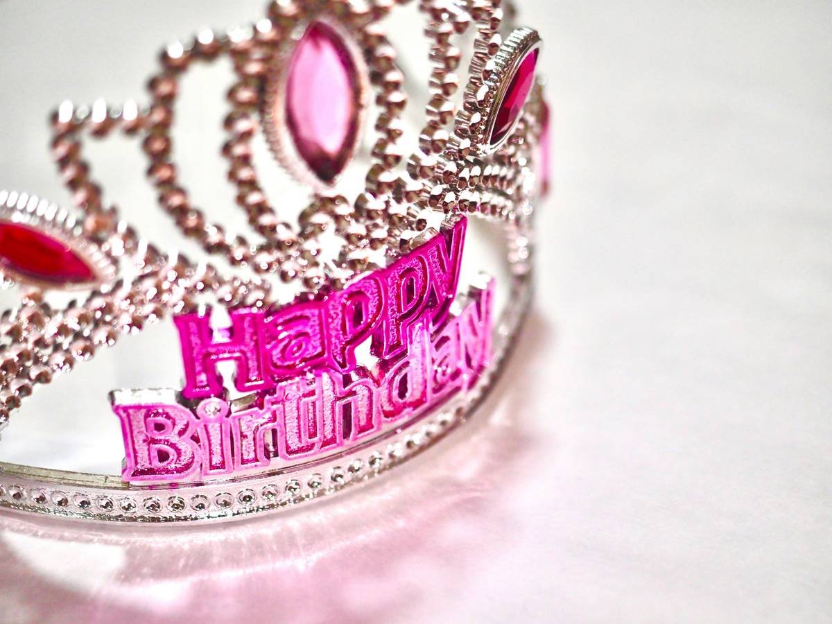 A close-up image of an elegant silver birthday tiara adorned with rhinestones and pearls.